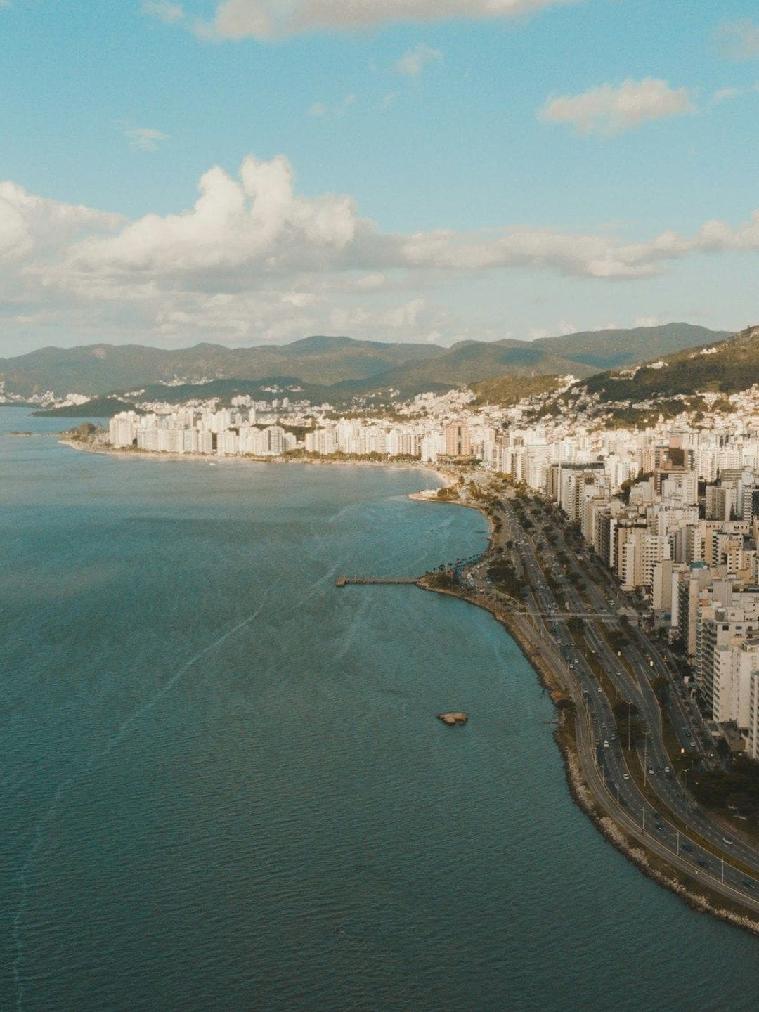 Vista aérea de Florianópolis ao entardecer, com a cidade junto ao mar